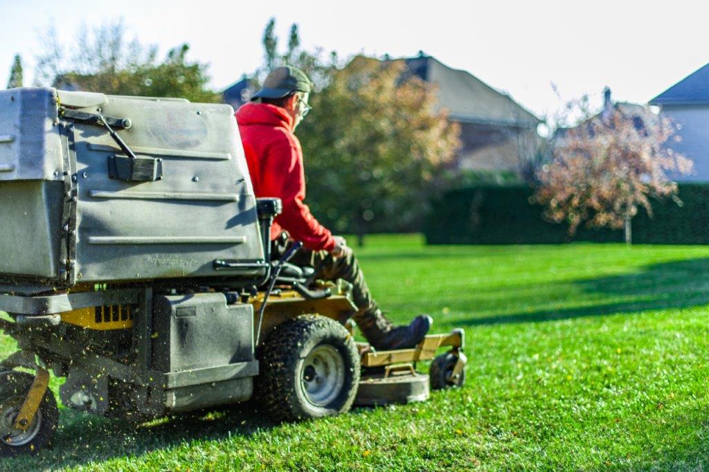 a man mowing a lawn on a riding lawn mower