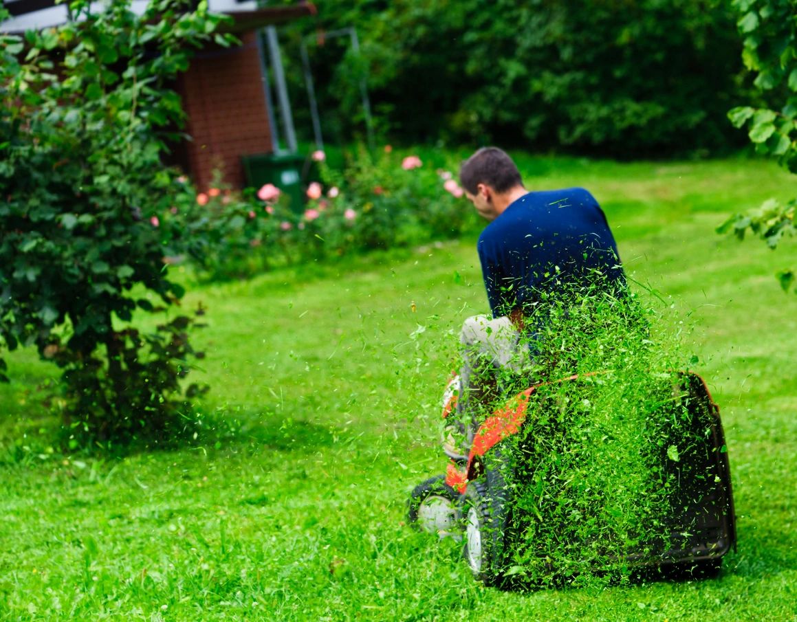 man mowing lawn on red riding lawnmower